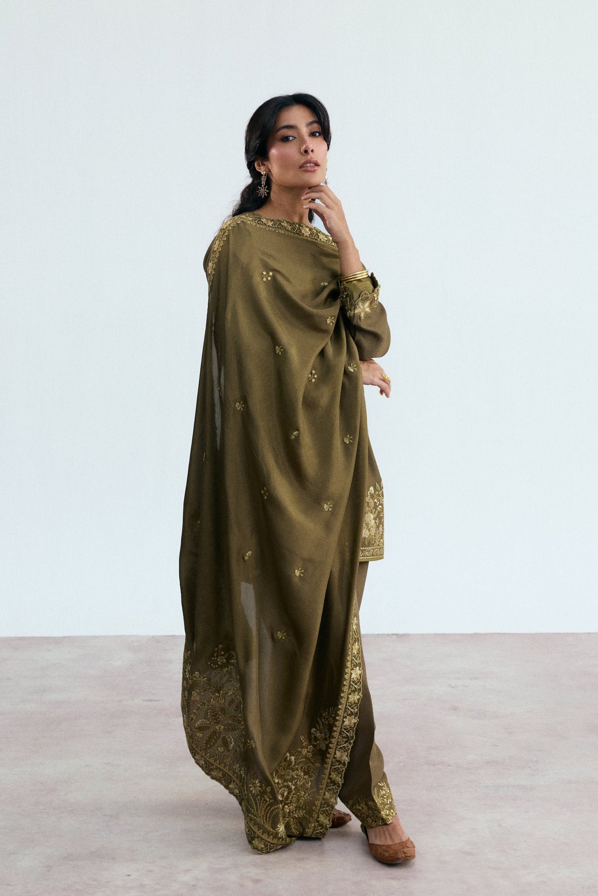 Full-length view of mehndi green Pakistani suit styled for a traditional mehndi or wedding function 