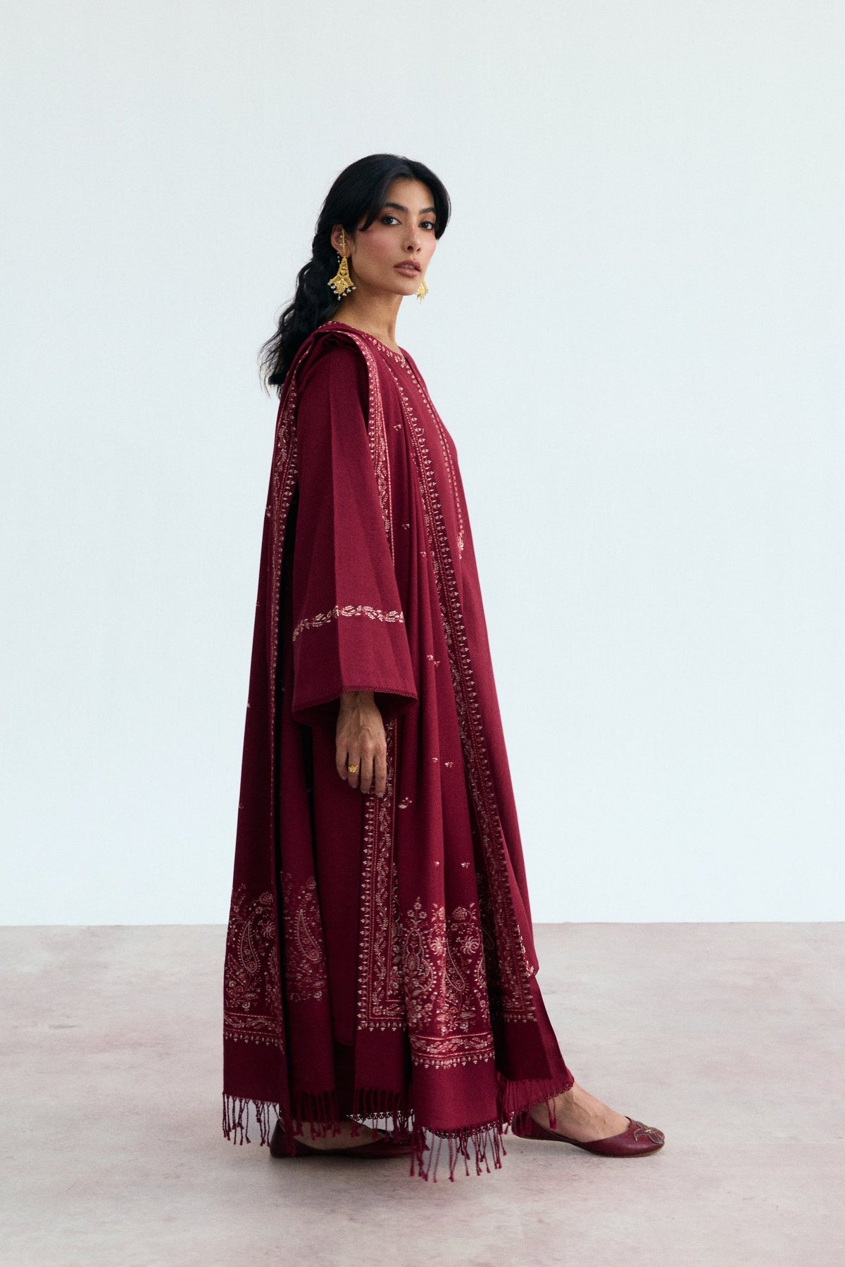 Deep red Pakistani khaddar three-piece suit with Kashmiri embroidery along sleeves and panel seams by Mannam
