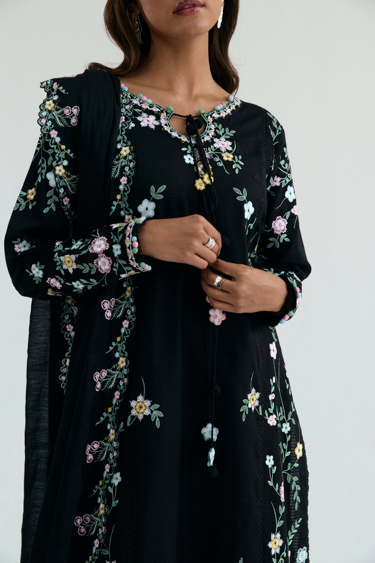 Close-up of asymmetrical neckline with lace accents and floral embroidery