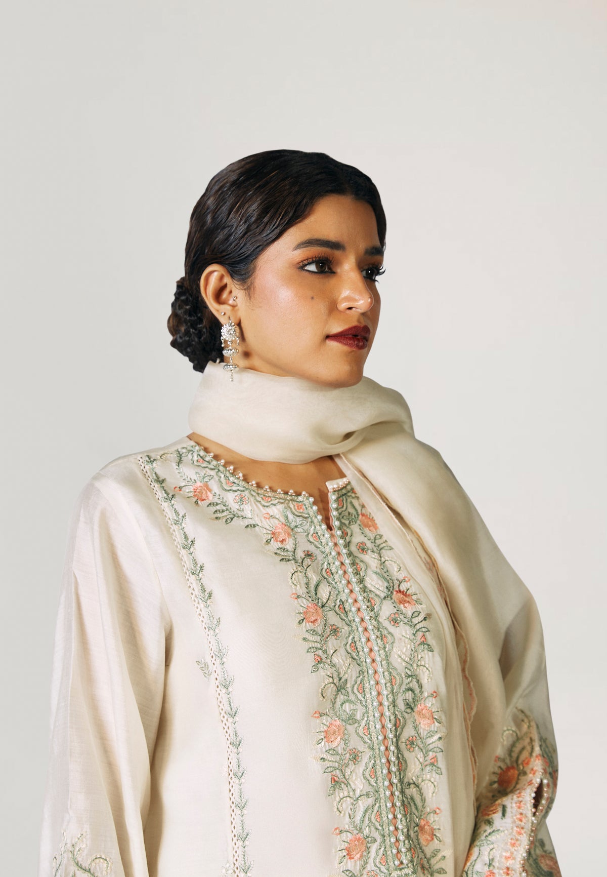 Side view of cream silk Pakistani kameez showing keyhole sleeve cut-out detail and floral embroidery along hem — formal ethnic wear by Mannam