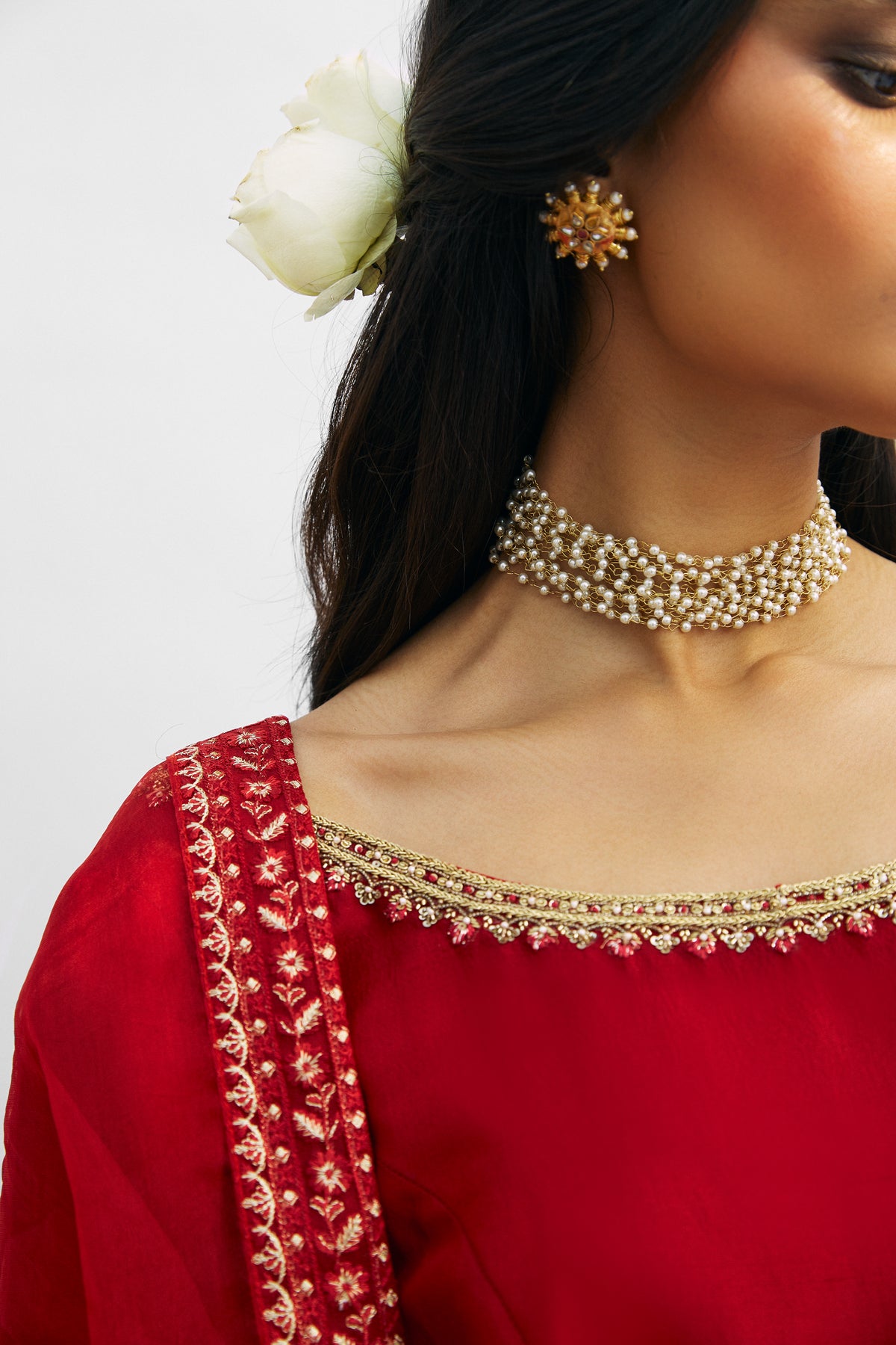 Side view of red raw silk Pakistani peshwas set with hand-embellished sleeve hem and organza dupatta by Mannam