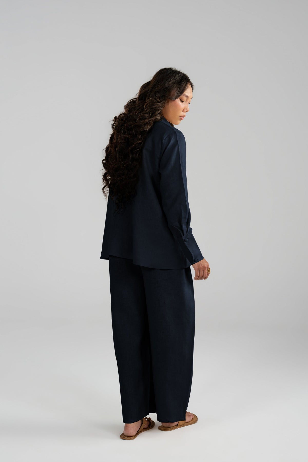 Back view of the Cove Set in navy blue pure linen, showing the long shirt and wide-leg panelled balloon trousers.